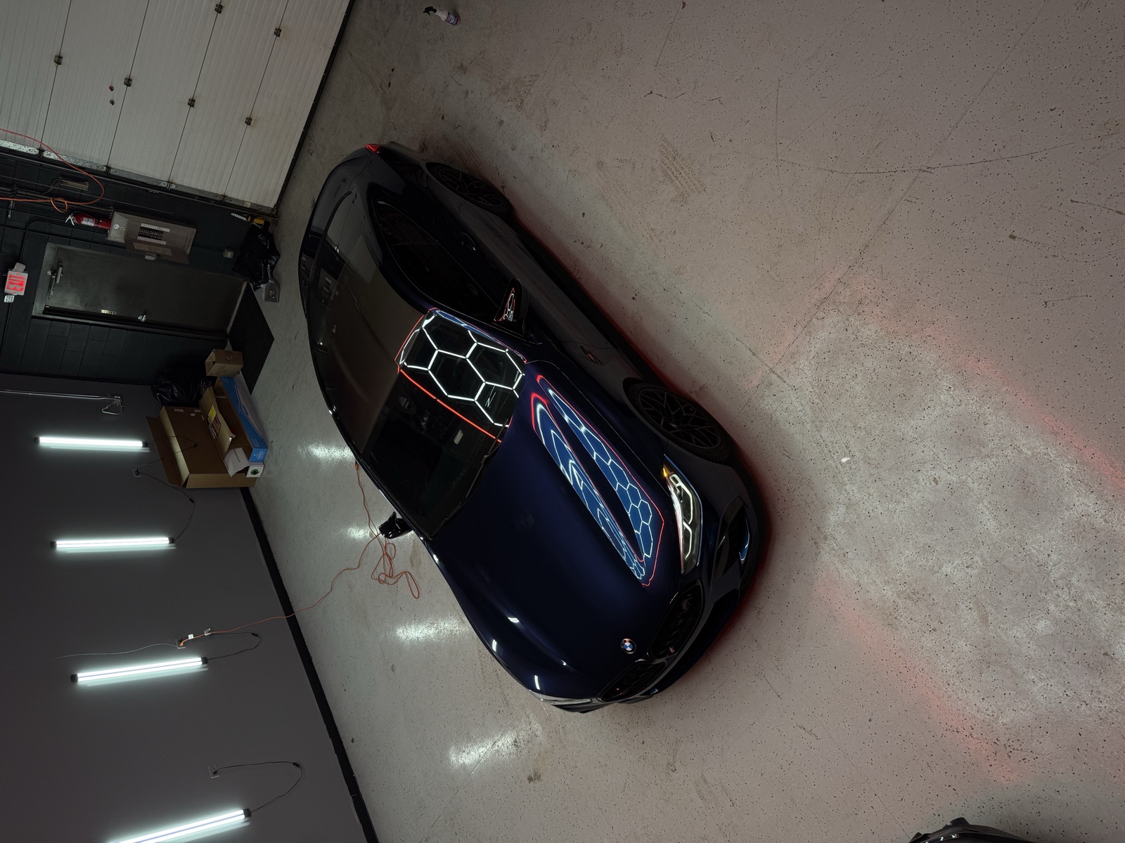 Blue BMW M8 with tinted glass under the shop lights