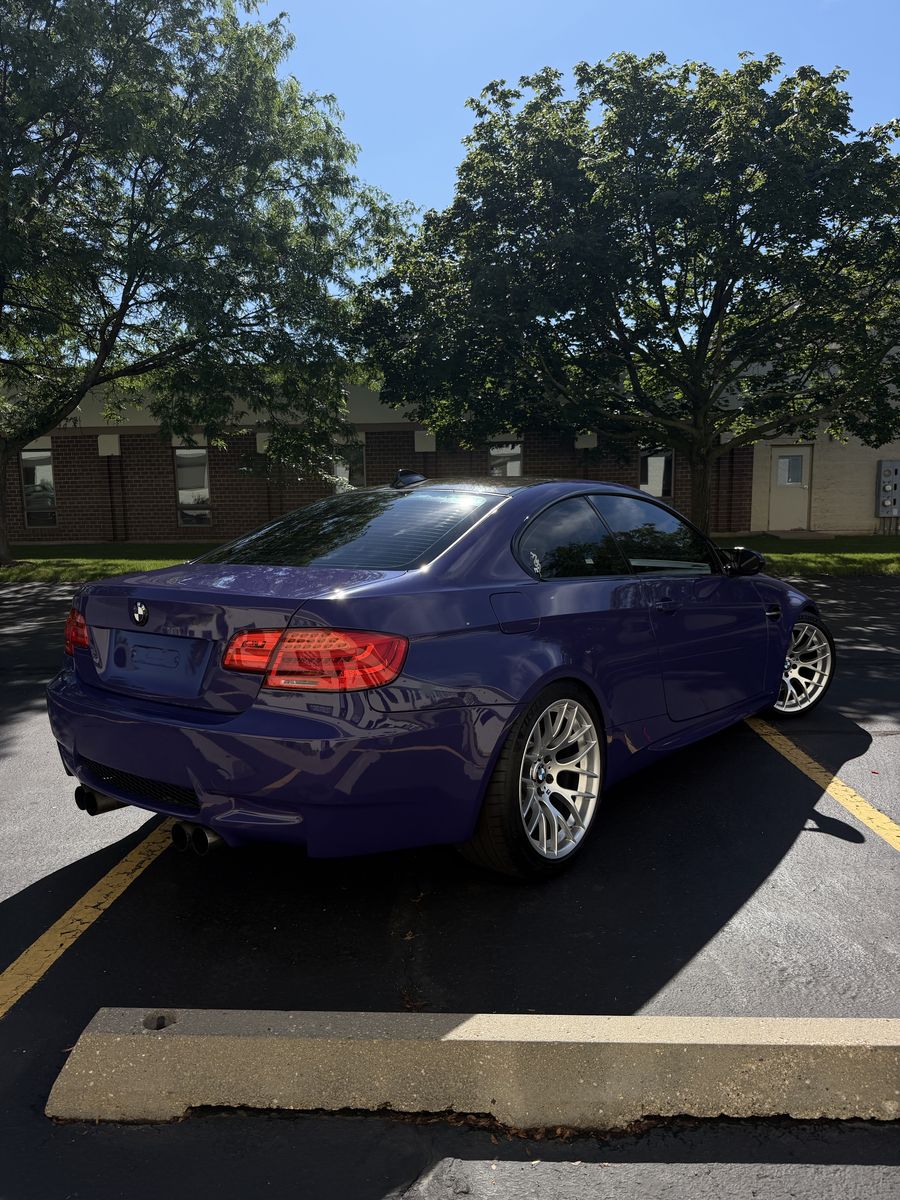 BMW M3 coupe in a purple wrap, rear three-quarter view with quad exhaust and silver forged wheels
