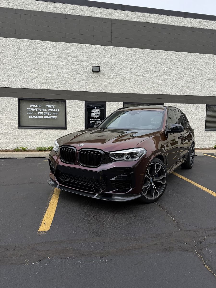 BMW X3 M in a deep burgundy wrap, front three-quarter view outside the Perfect Graphics shop