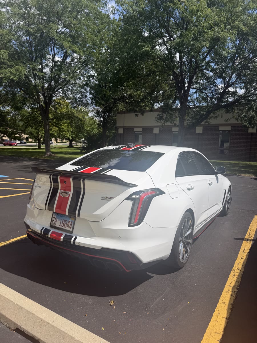 Rear three-quarter of the white Cadillac CT4-V Blackwing, stripes running over the trunk and spoiler