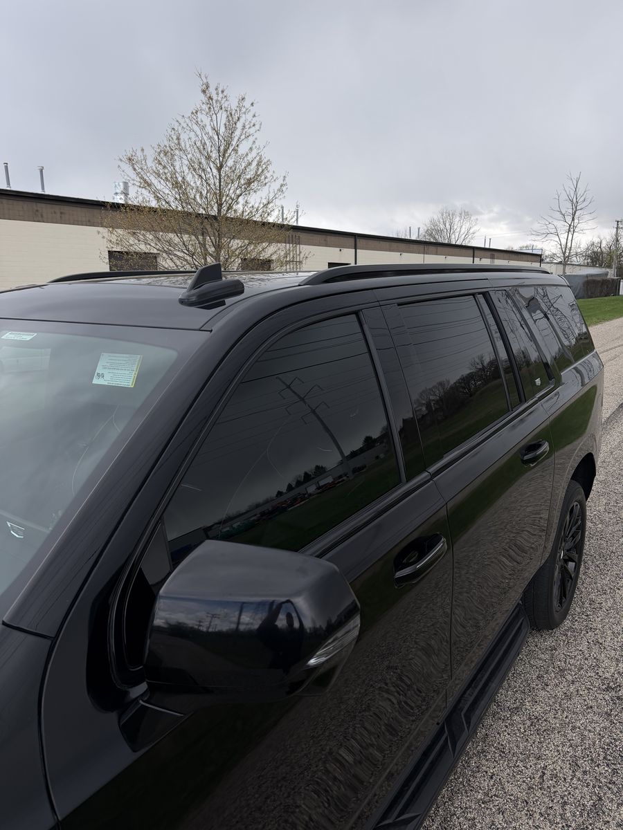 Black Chevrolet SUV with the window surrounds, roof rails and mirror caps finished in black