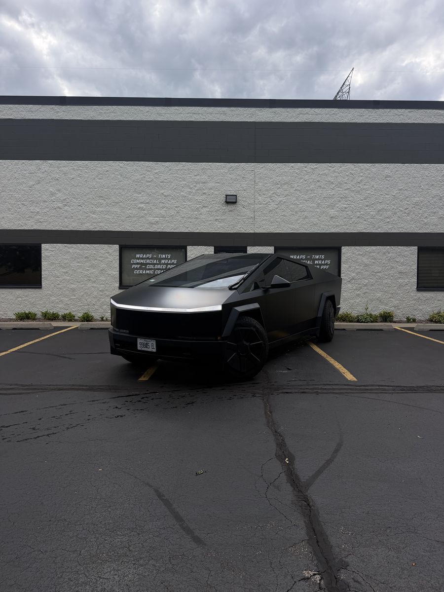 Tesla Cybertruck in a matte black wrap, parked outside the Perfect Graphics shop