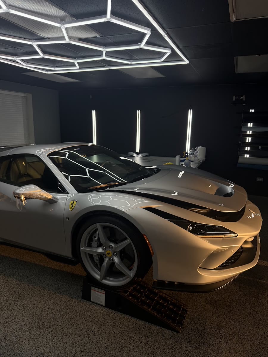 Silver Ferrari F8 up on the ramps in the bay under the hex lighting