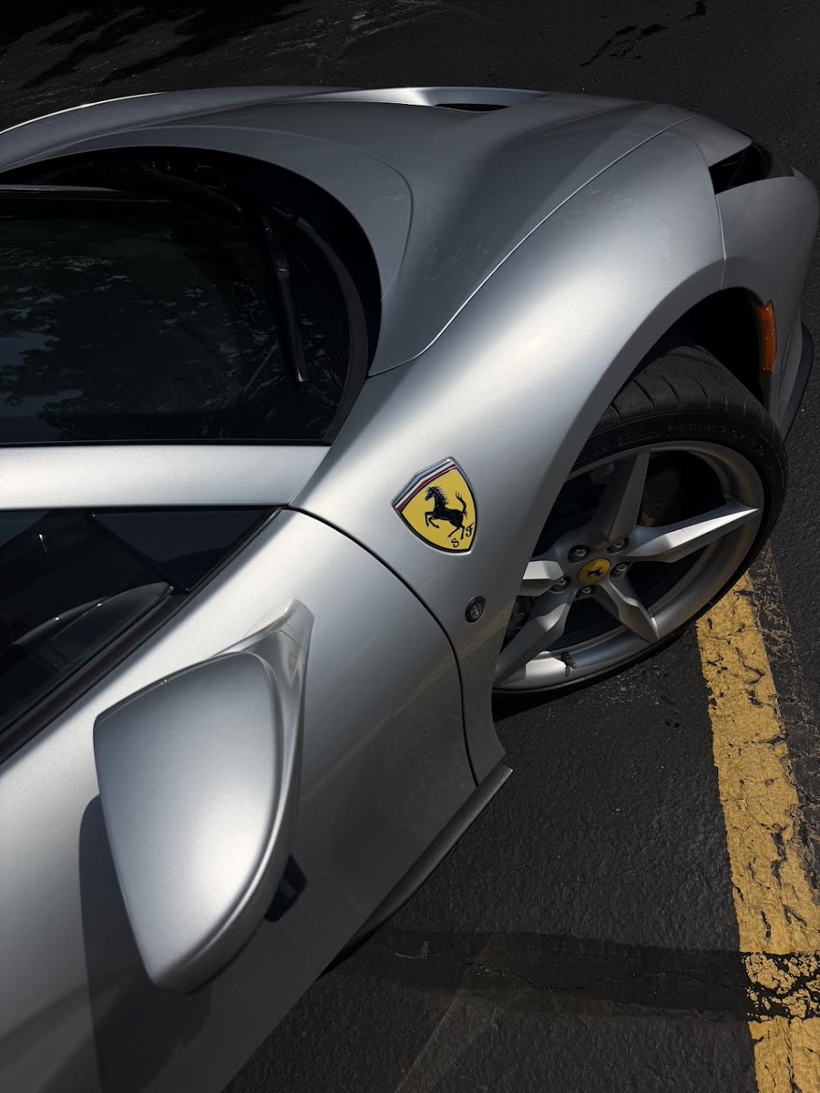 Front fender and Ferrari badge on the silver F8, shot low over the wheel