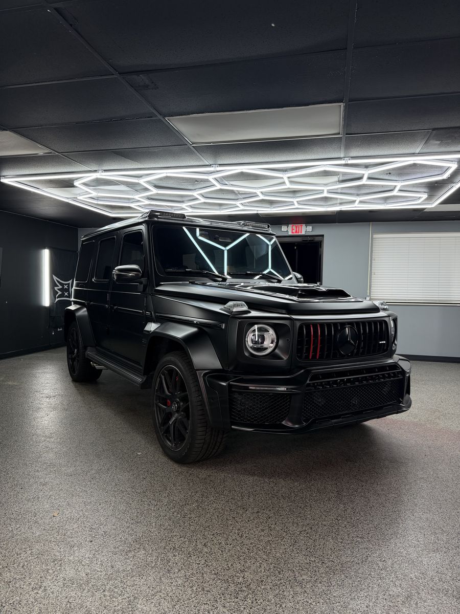 Mercedes-AMG G-Class blacked out, front three-quarter beneath the hex lighting