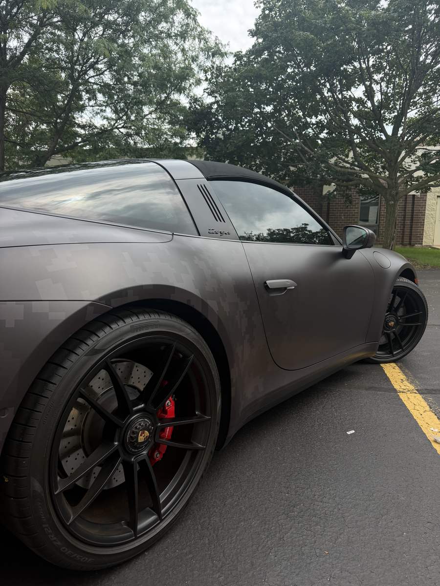 Porsche 911 Targa 4 GTS in a matte digital camo wrap, side profile on the satin black wheels