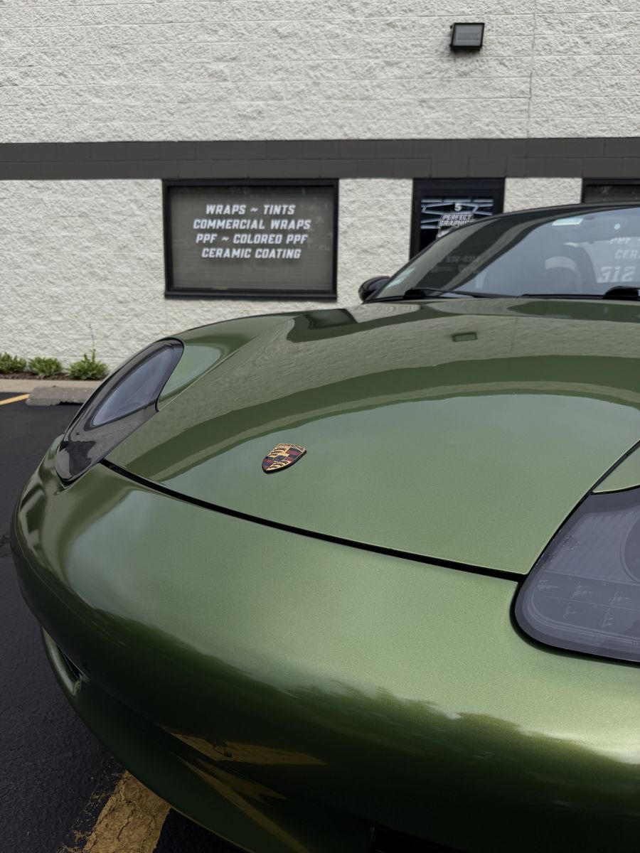 Hood and headlight of an olive green wrapped Porsche