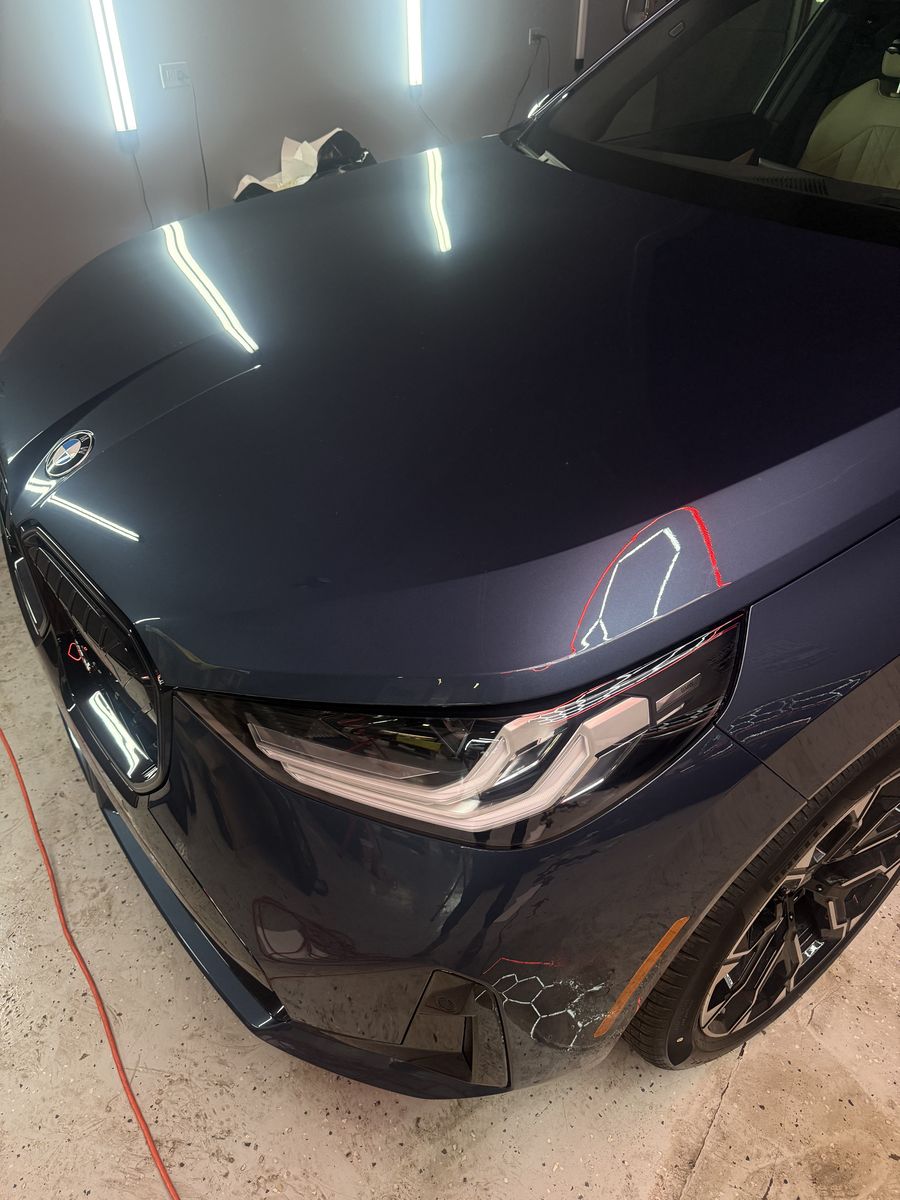 Navy BMW with paint protection film going on across the hood and front fender