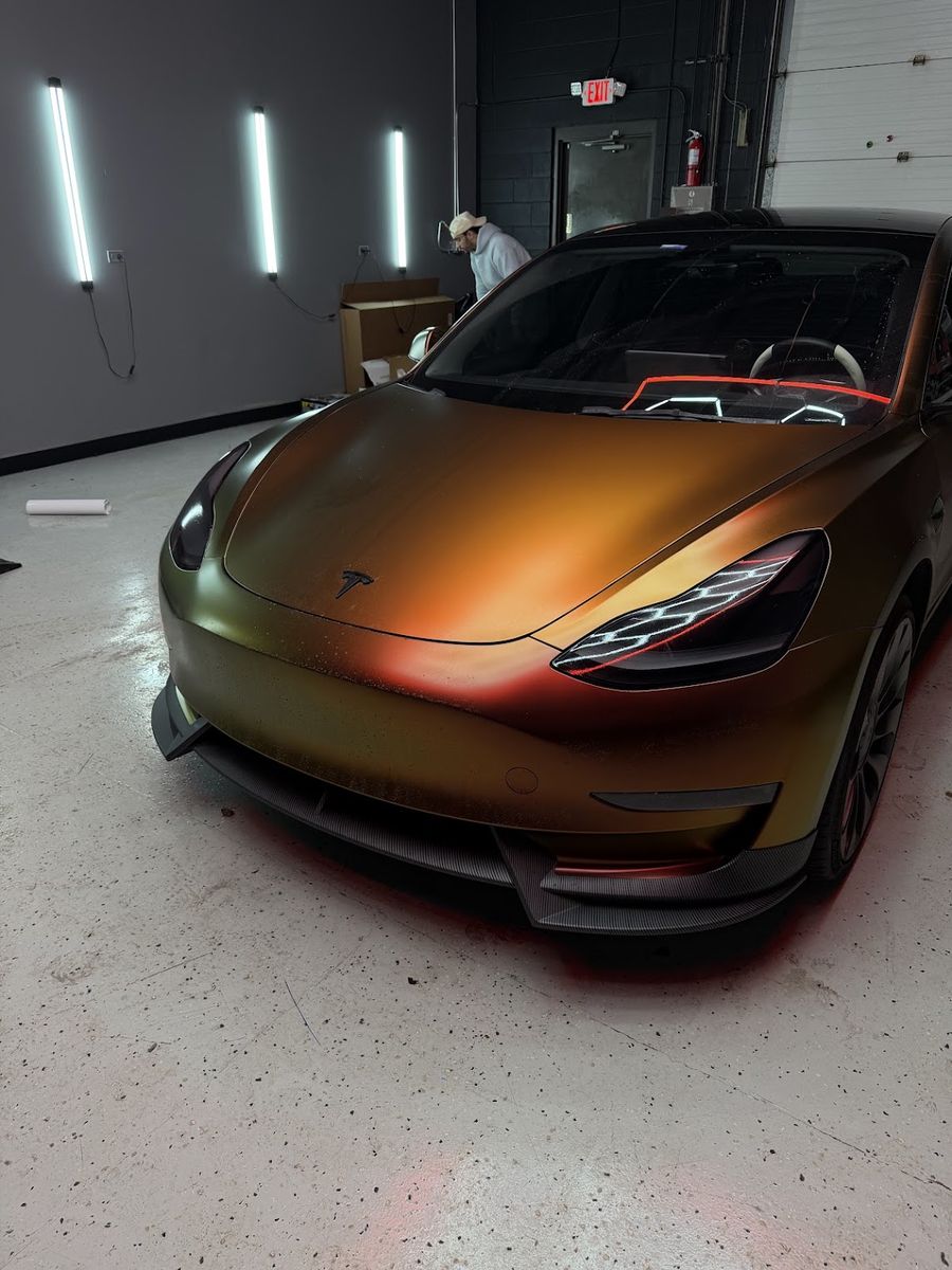 Tesla Model 3 in a gold and bronze color shift wrap, inside the shop